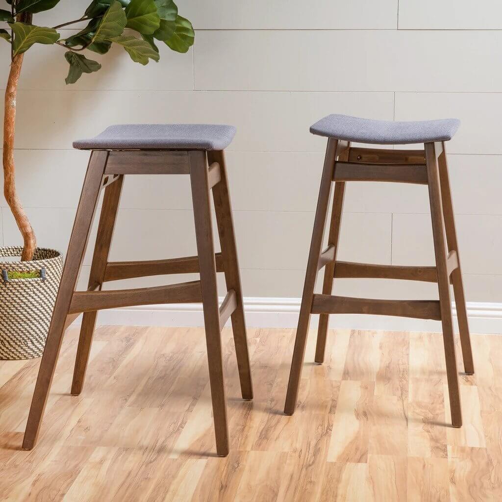 A pair of mid century bar stools sitting on top of a hard wood floor
