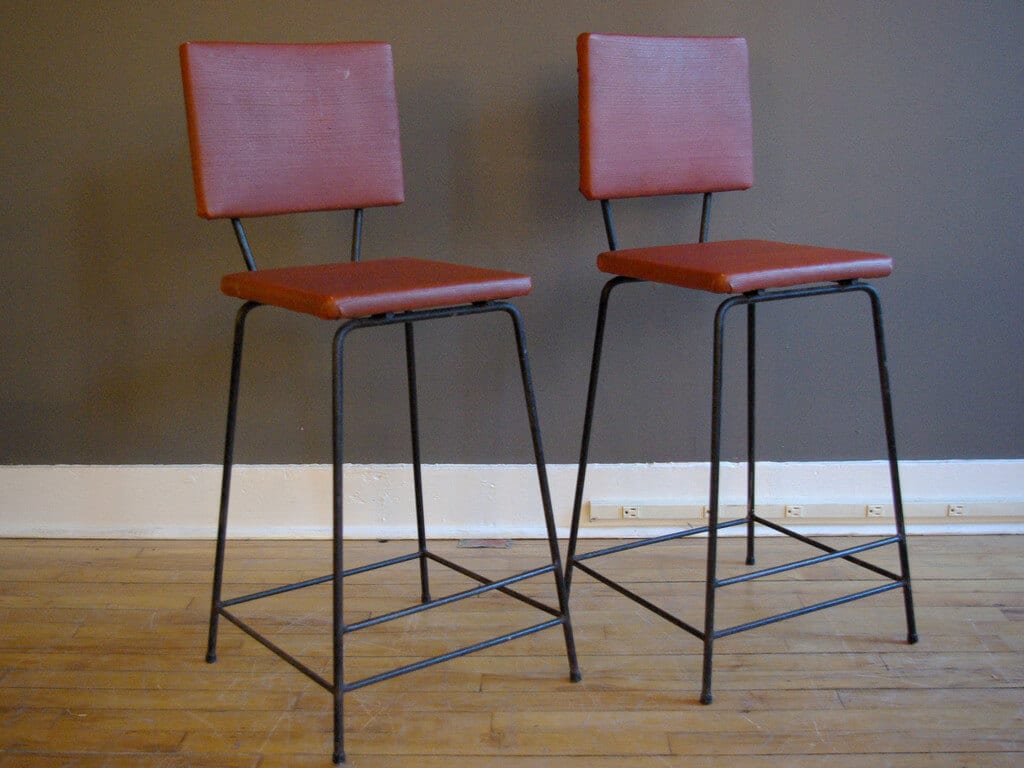 A pair of mid century modern bar stools sitting on top of a hard wood floor
