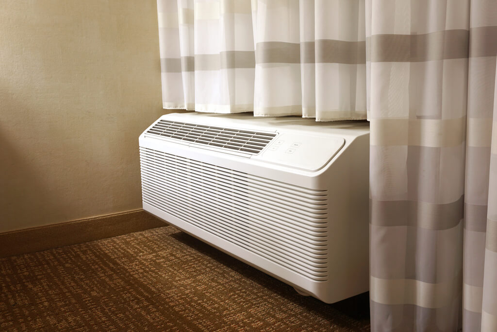 A white air conditioner sitting next to a window
