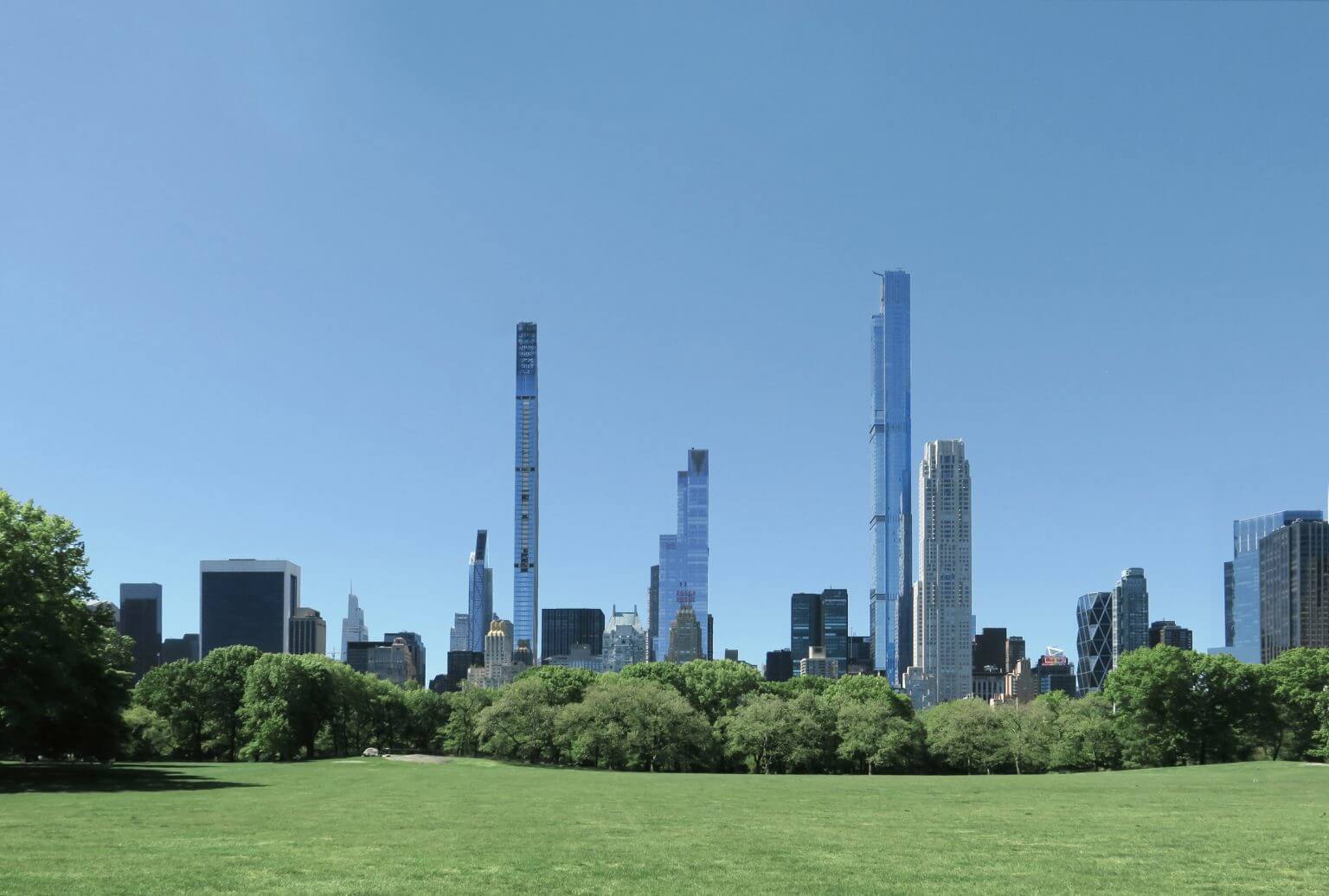 A grassy field in front of a city skyline
