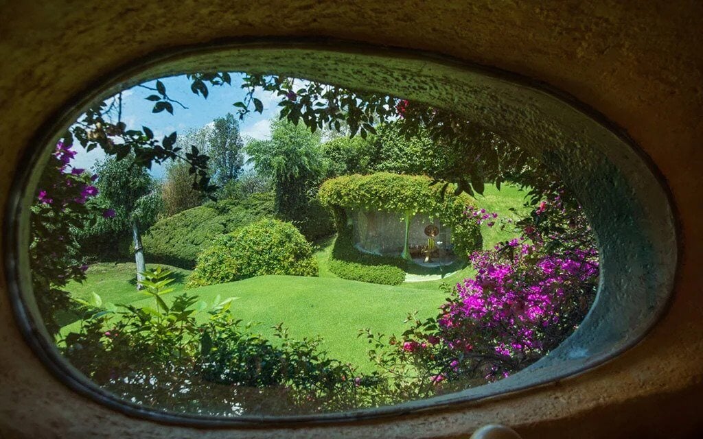 A view of a garden through a round window
