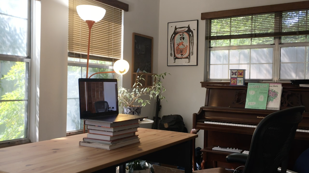 A room with a desk, piano, and a lamp
