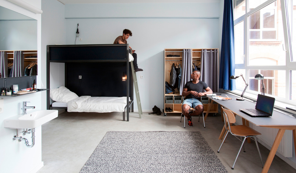 A man standing on a bunk bed in a bedroom
