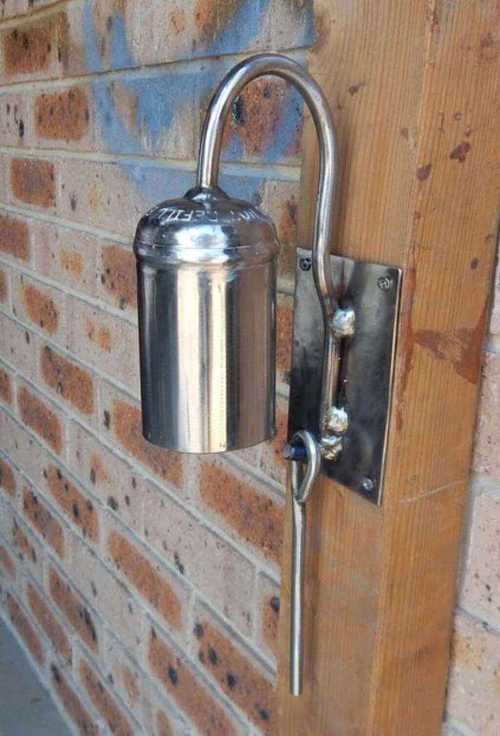 A unique door bell is attached to a brick wall
