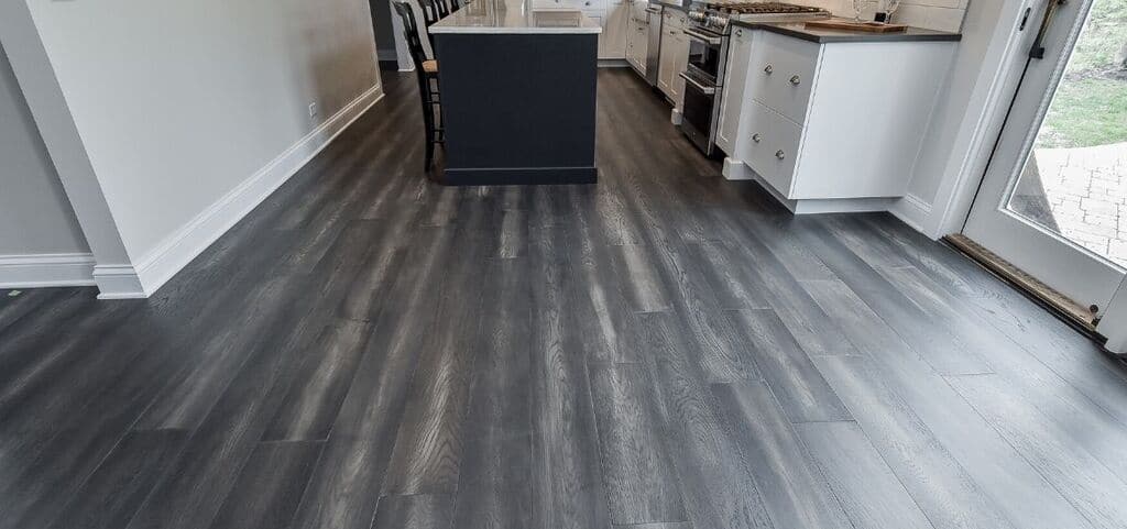 A kitchen with white cabinets and wood floors
