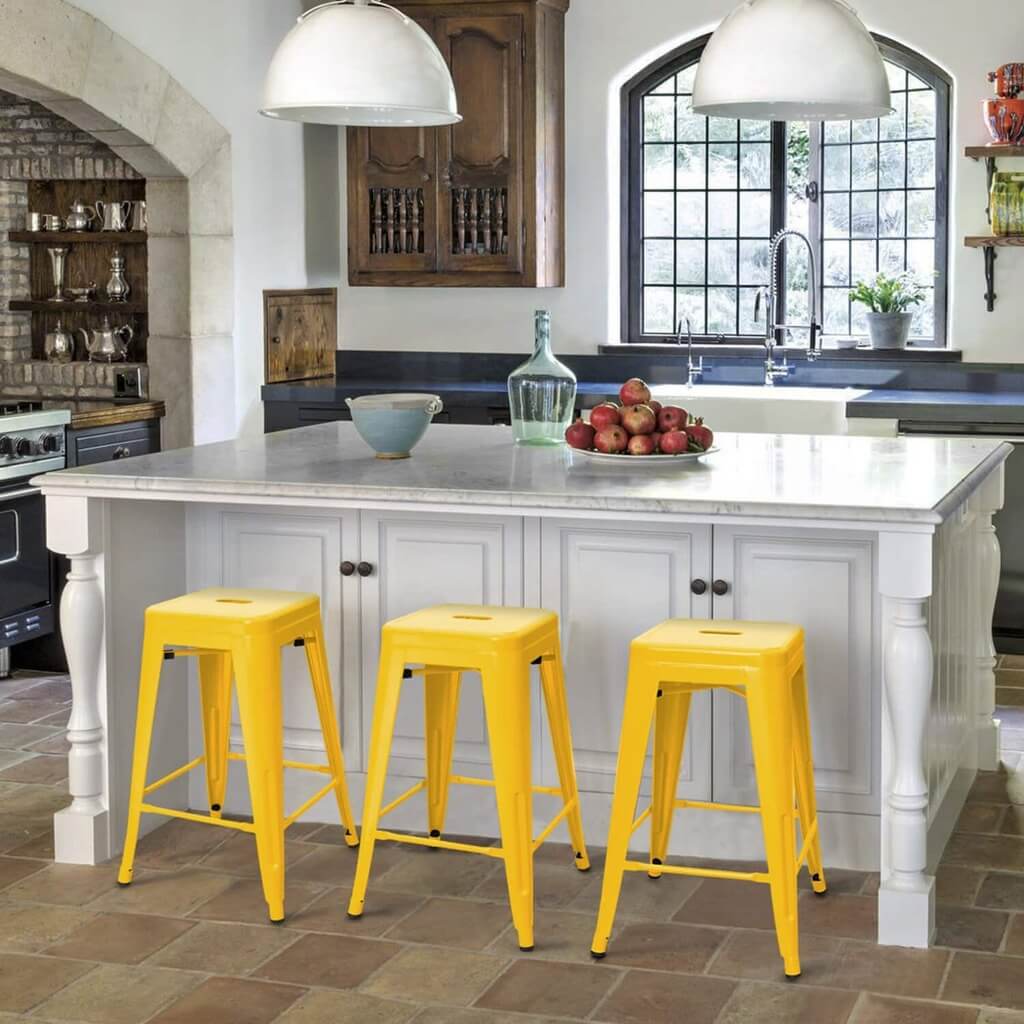 A kitchen with three yellow stools and a center island
