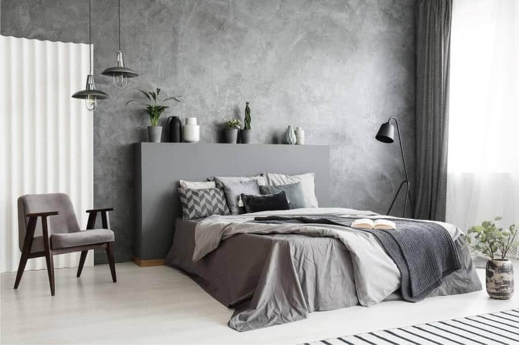 A bedroom with grey walls and a bed
