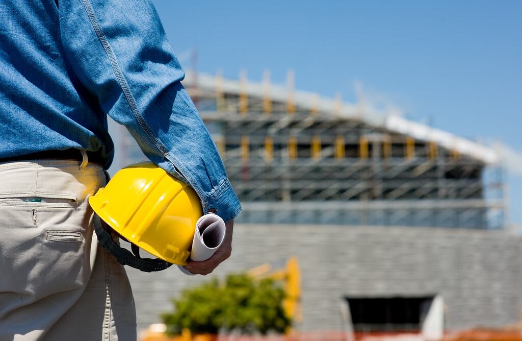 A construction worker holding a yellow helmet


