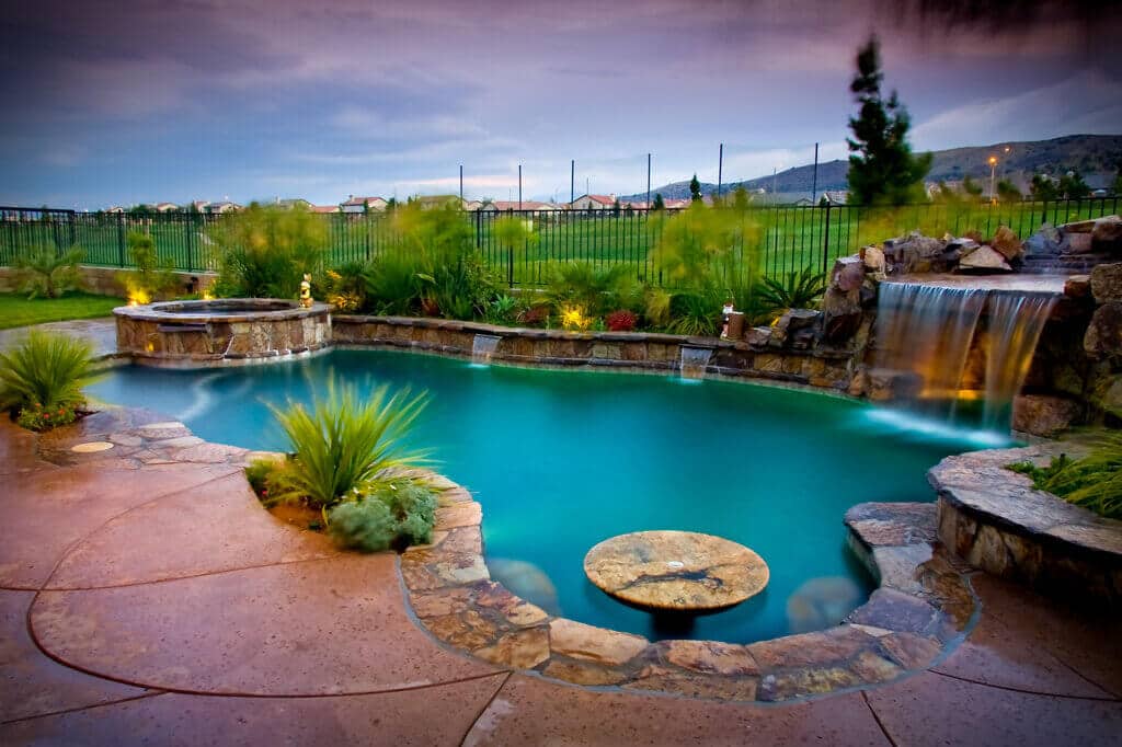 A pool with a waterfall and a fire pit
