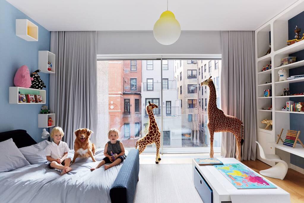 A group of children sitting on a bed in a bedroom
