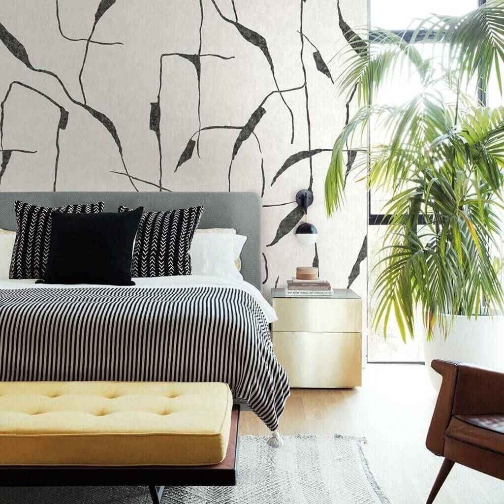 A bedroom with a bed and a plant in the corner
