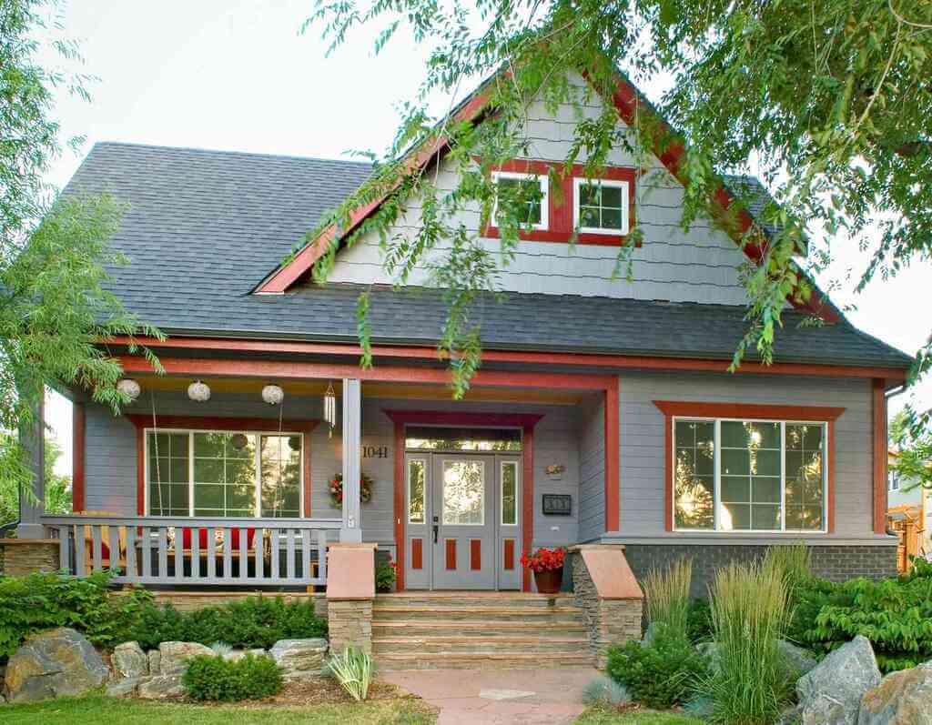 A gray house with red trim and a porch
