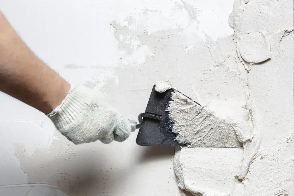 Stucco Repairs : A person using a paint roller to paint a wall
