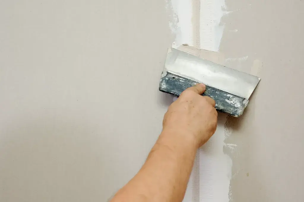 Stucco Repairs: A person using a paint roller to paint a wall
