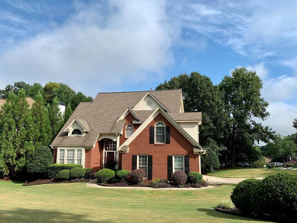 A red brick house surrounded by trees and bushes
