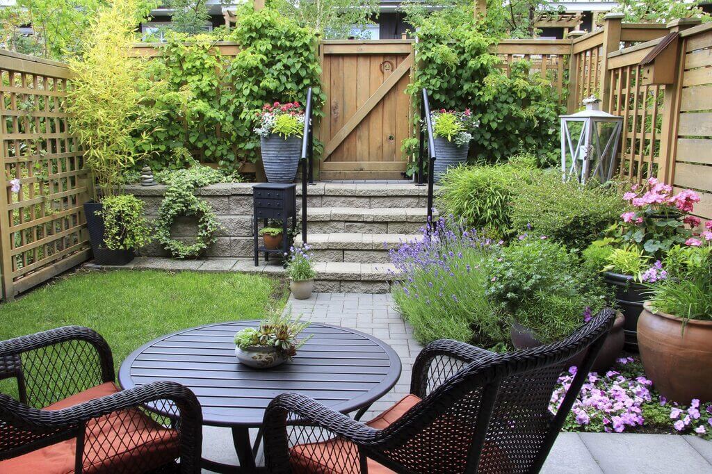 A patio with a table, chairs, and potted plants
