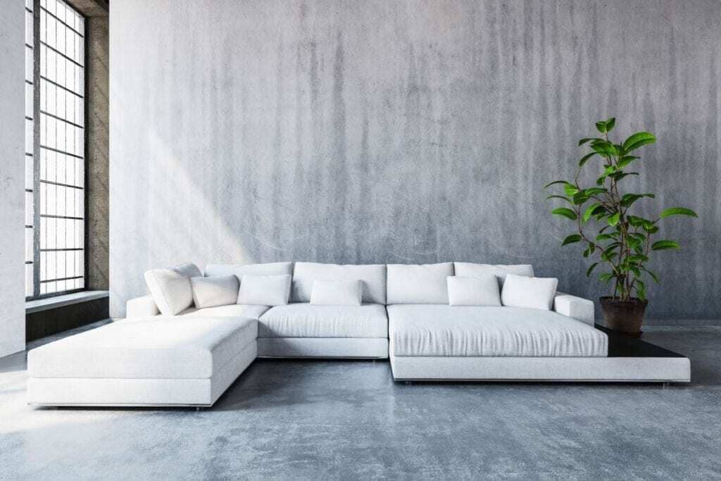 A large white couch sitting in a living room next to a potted plant
