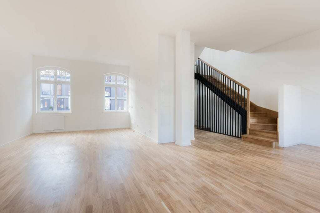 An empty room with wooden floors and a staircase
