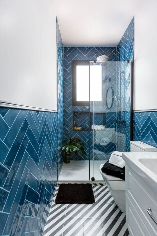 A bathroom with blue tiles and a black and white floor
