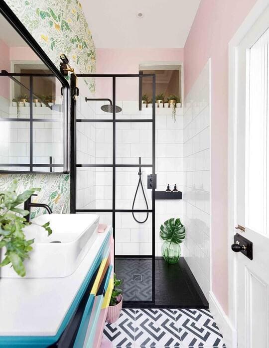 A bathroom with pink walls and a black and white floor
