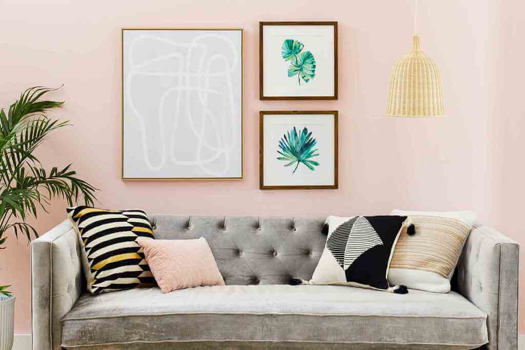 A living room with pink walls and a gray couch
