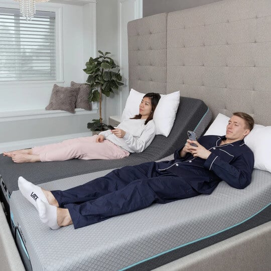A man and a woman laying on top of a Drift Classic - Adjustable Bed Frame
